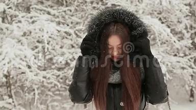 在白雪覆盖的杉树的<strong>背景</strong>下，一个年轻漂亮的女孩穿着<strong>暖冬</strong>的衣服，带着一个引擎盖，不被遮挡